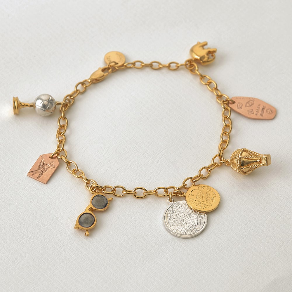 paper shot of gold plated , rose gold and silver Globe Trotter Charm Bracelet by Alex Monroe Jewellery