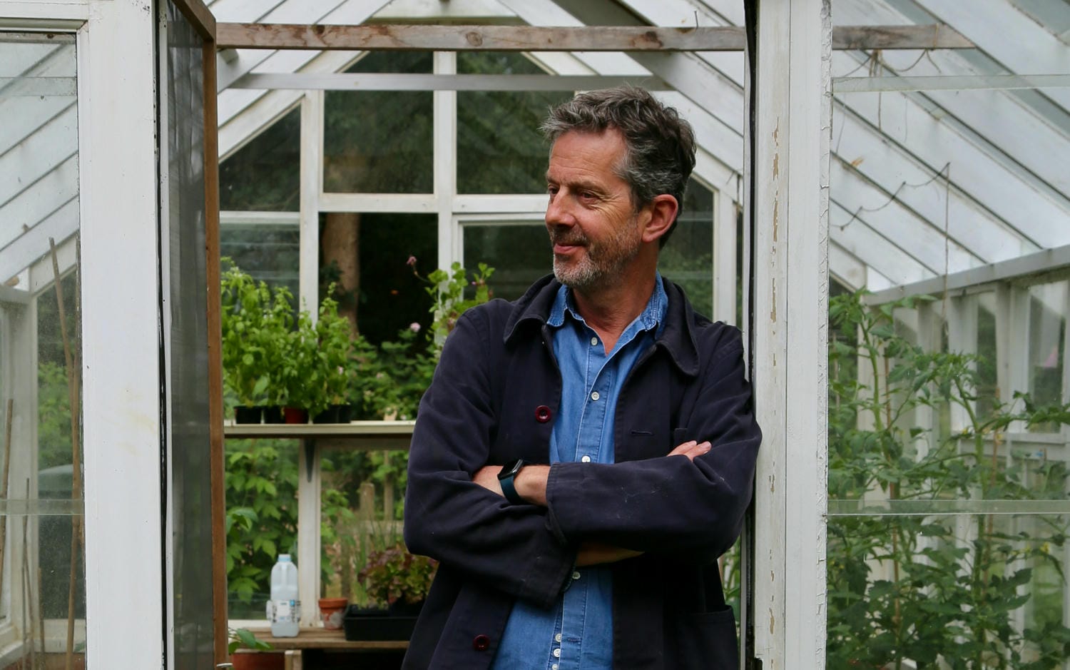 Alex leaning against a pillar in his greenhouse in Suffolk.