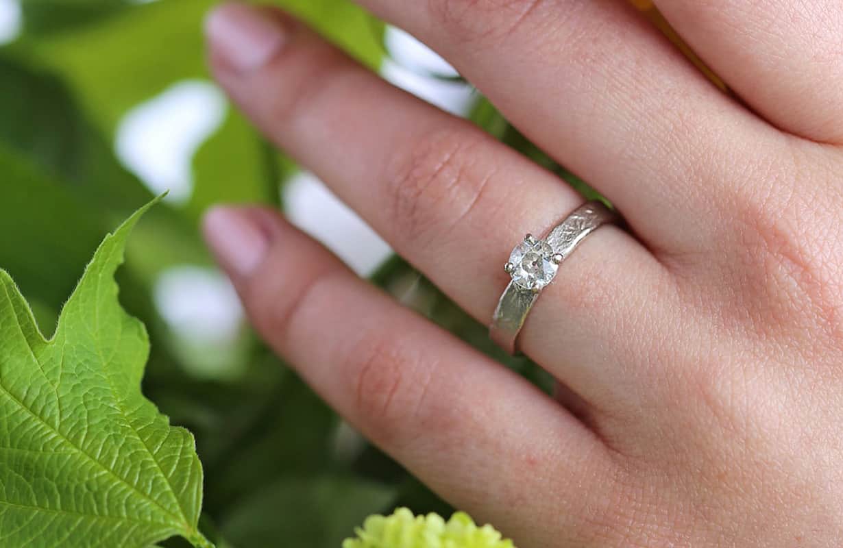 Three dark green emerald gemstones scattered on a white surface.