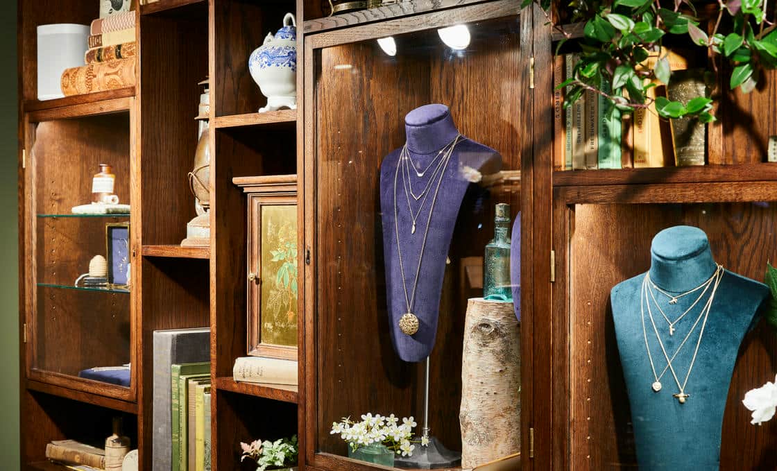 Wooden jewellery display cabinets full of blue and velvet jewellery display busts and nature inspired props.