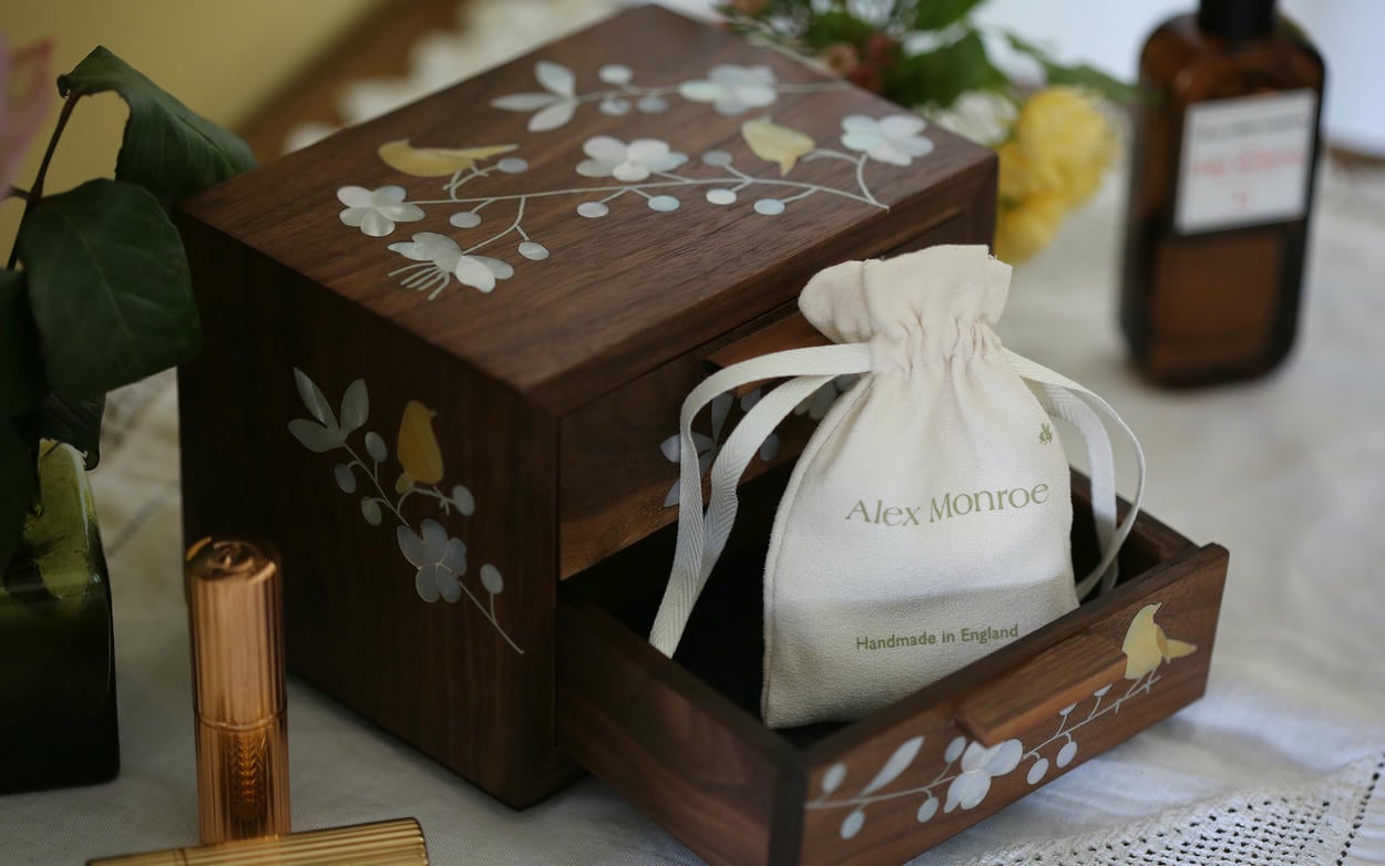Wooden jewellery box with mother of pearl floral and bird details, with 1 open drawers containing a fabric pouch.