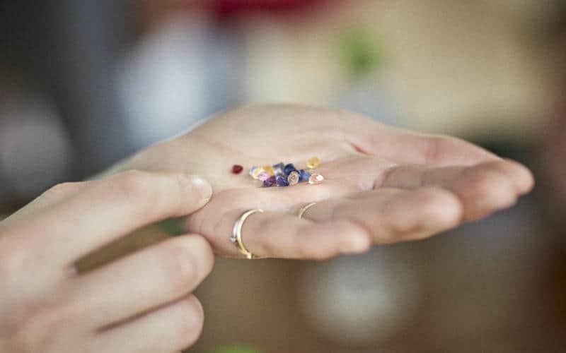 Hand held out with a selection of coloured sapphire gemstones held in the palm.