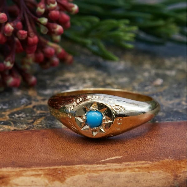 Signet ring with engraving and turquoise gemstone in a star cut setting.