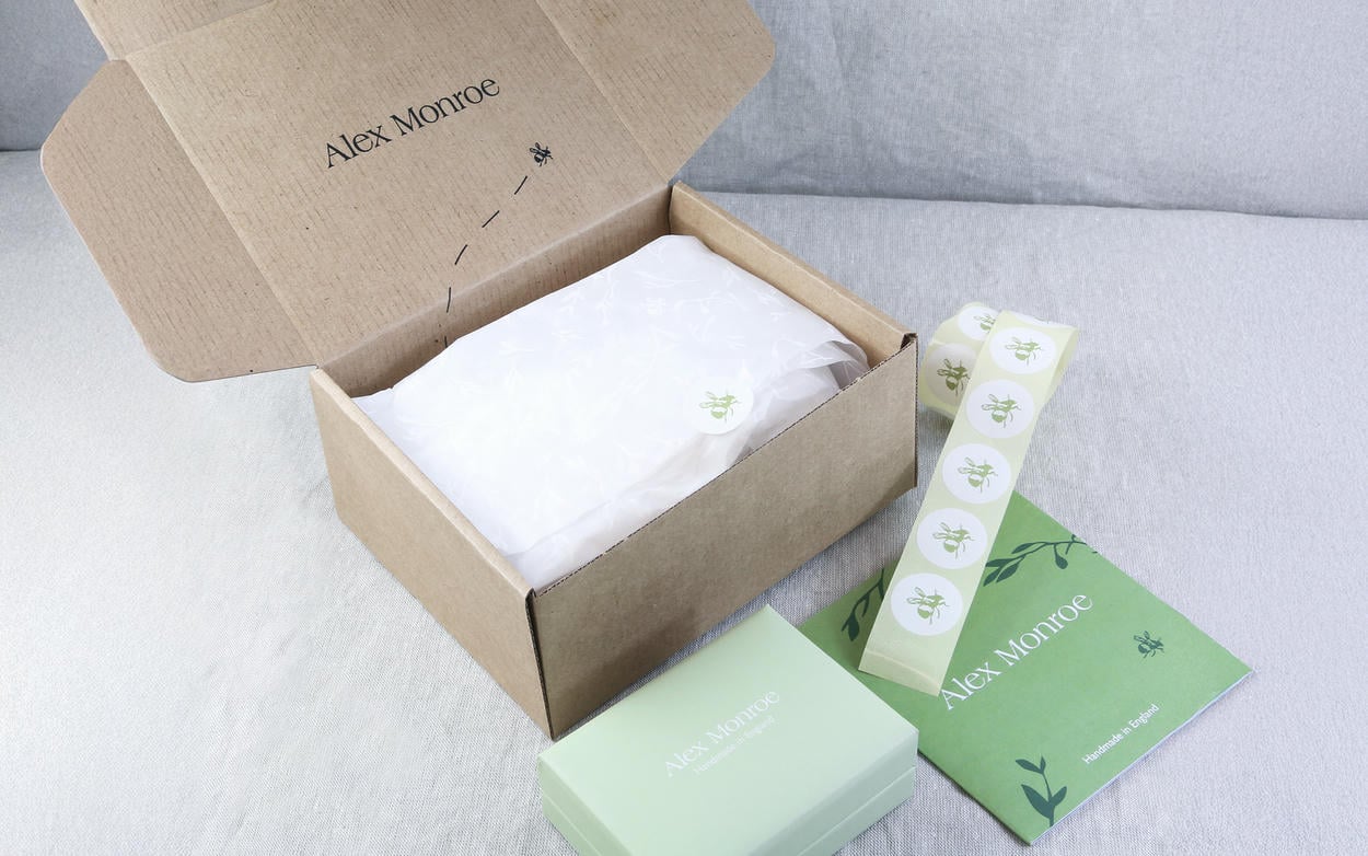 Alex Monroe jewellery packaging including sage green jewellery box, branded mailing box, tissue paper and stickers.