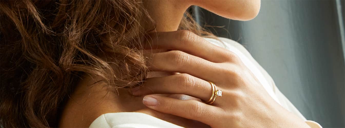 Close up of a woman wearing a solid gold engagement ring.