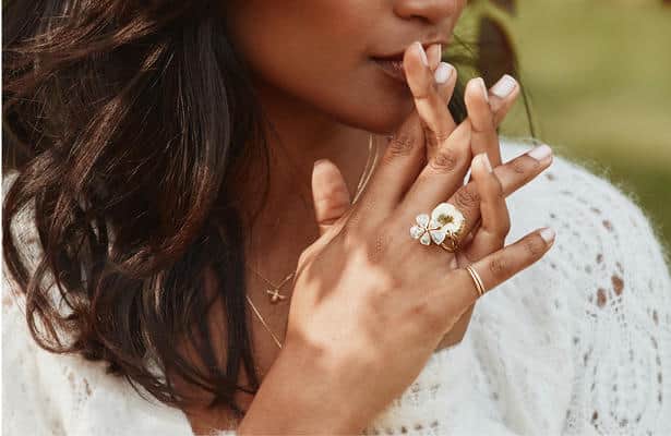 Woman wearing a large flower shaped diamond set engagement ring.