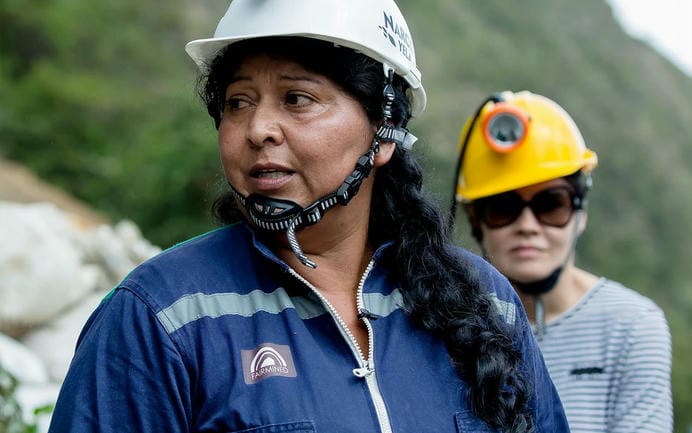 Female miner wearing blue Fairmined Gold overalls, white safety helmet.