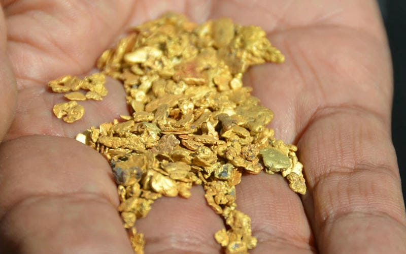 Raw gold pieces held in the palm of a hand.