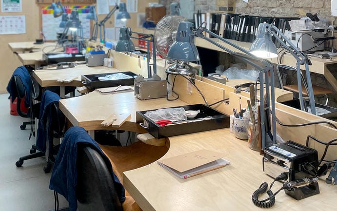 Jewellery making benches with angle poise lamps and assorted tools in a large jewellery workshop.