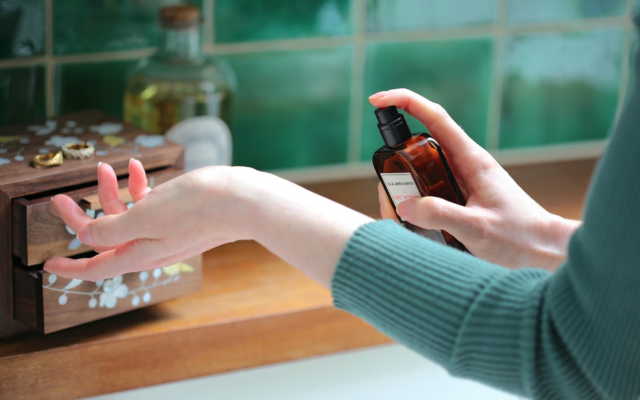 A woman spryaing perfume on her wrist