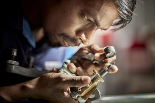 Lapidarist using a loupe to inspect the facet he has cut in a Sri Lankan Sapphire.