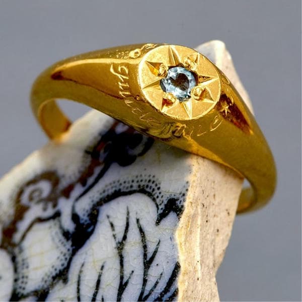 Signet ring with engraving and aquamarine gemstone in a star setting.