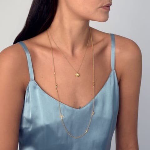 Model in blue dress wears Starfish Constellation Long Necklace and shell necklace layered