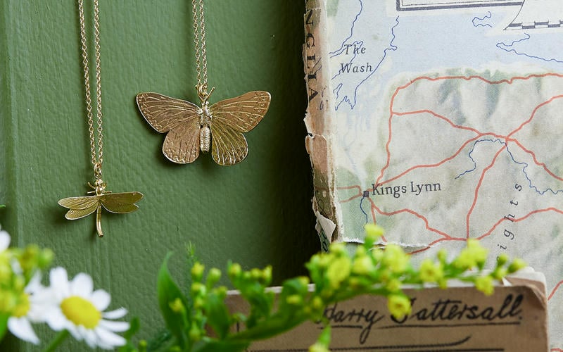 Suffolk landscape of green filds, hedges, trees and blue sky with wispy white clouds. A wooden telephone pole in the foreground.