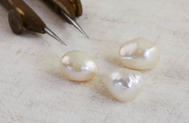 Three pearlescent white pearls scattered on a white surface.
