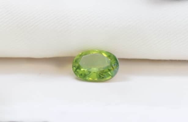 One large green peridot gemstone on a white surface.