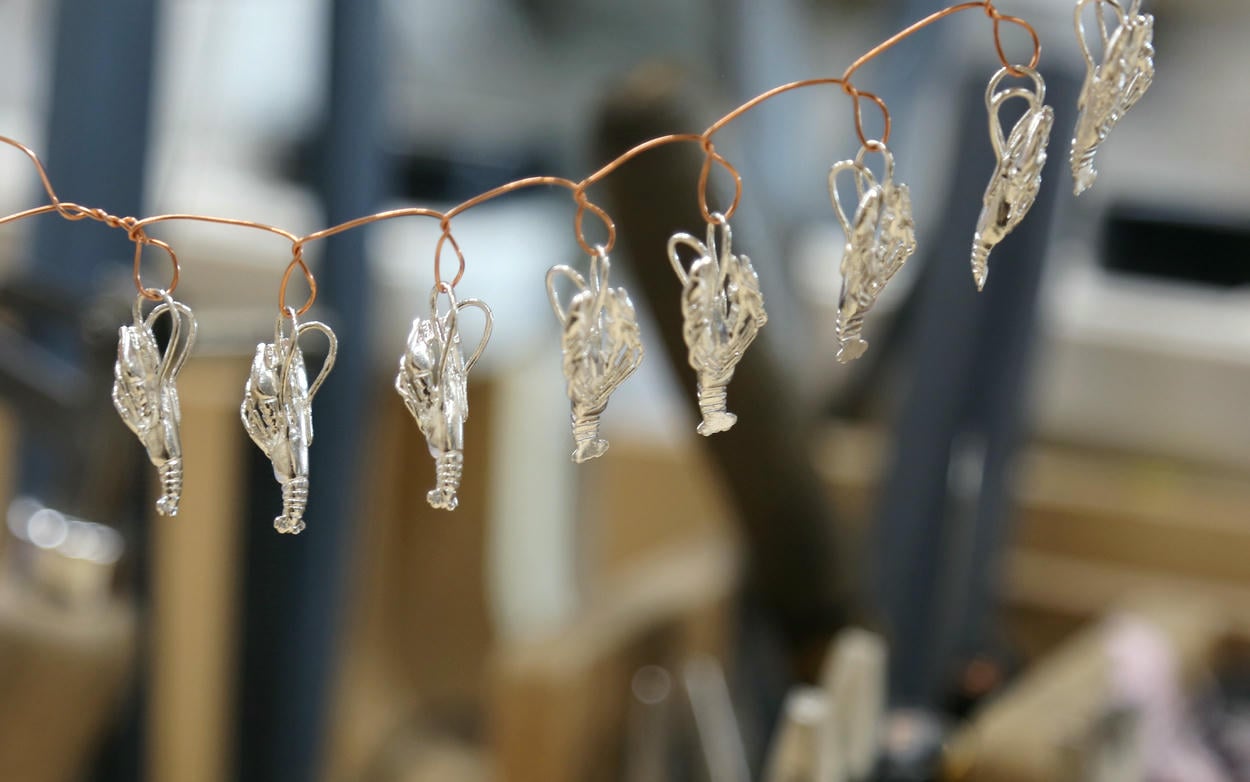 Eight silver lobster charms looped on a piece of wire.