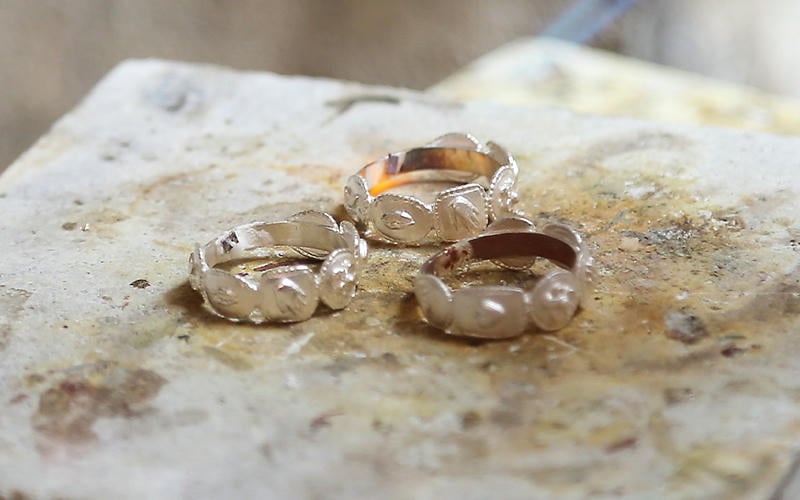 Three silver rings grouped on a furnace plate in a jewellery workshop.