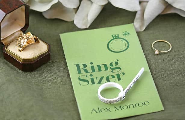 White plastic ring sizer on a green background.