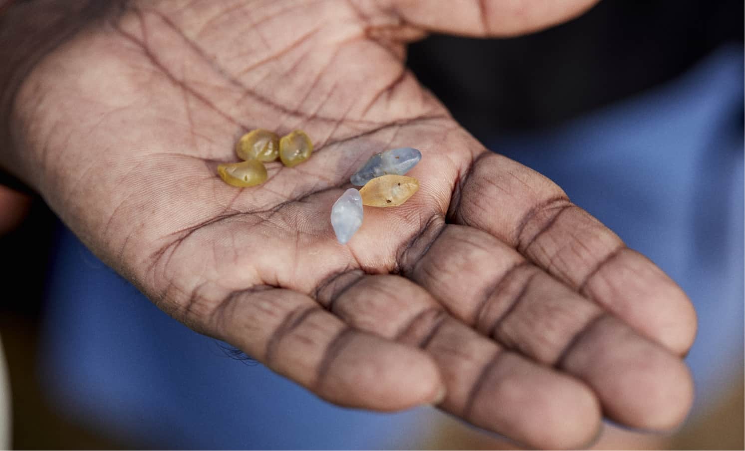 A selection of rough sapphires held in the palm of a hand.