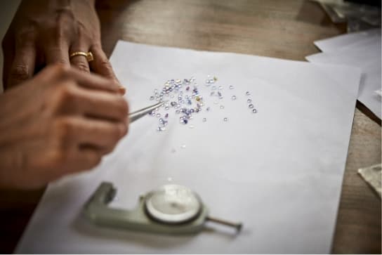 A selection of small, freshly cut Sri Lankan mined sapphires being delicately selected and inspected with tweezers.