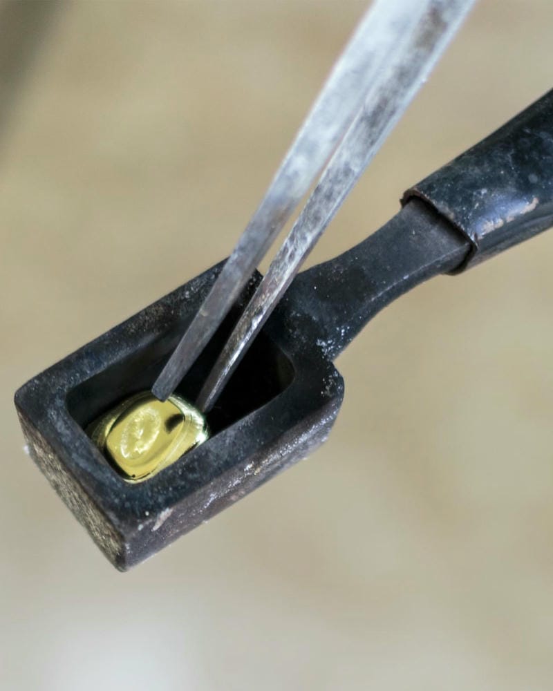 Small cube of fairmined stamped gold held in a cast iron crucible.