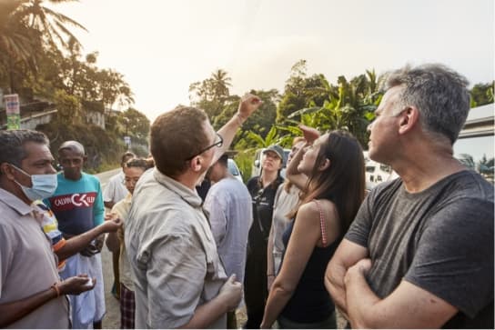 The group studying the uncut sapphires under the sunlight at a gemstone street market in Sri Lanka.