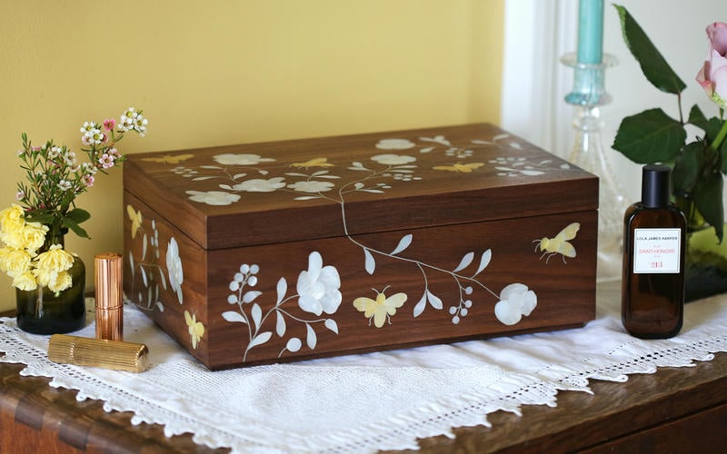 Wooden jewellery box with mother of pearl flower and bee pattern.