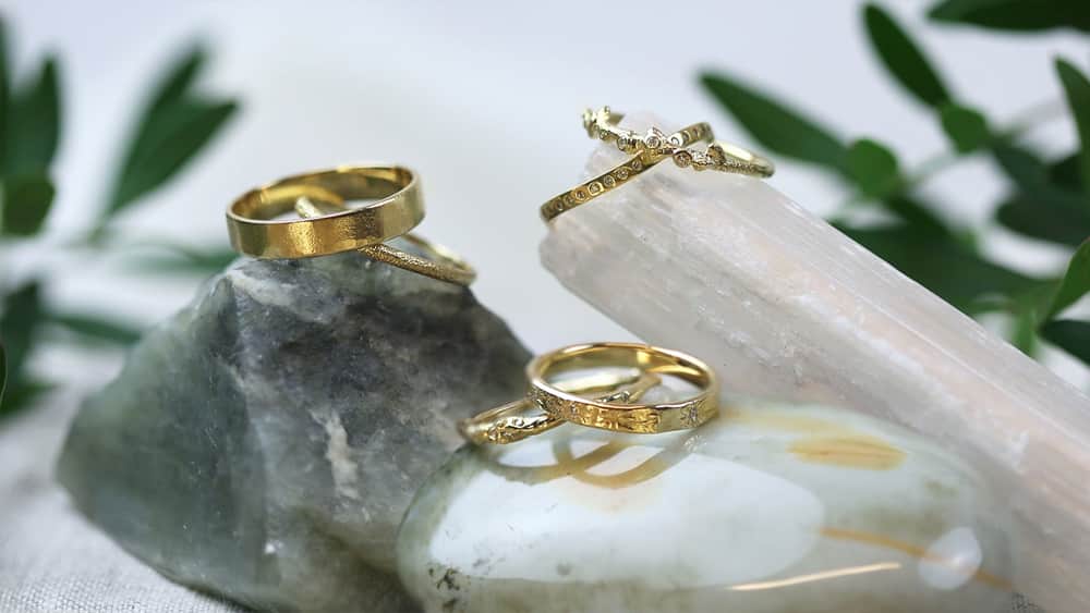 Selection of solid gold 18ct yellow wedding bands on polished stones.