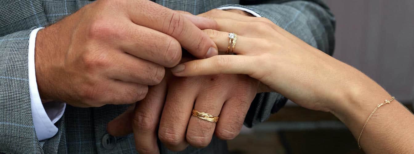 Woman wearing a white gold wedding band set with diamonds and a diamond trilogy white gold engagement ring.