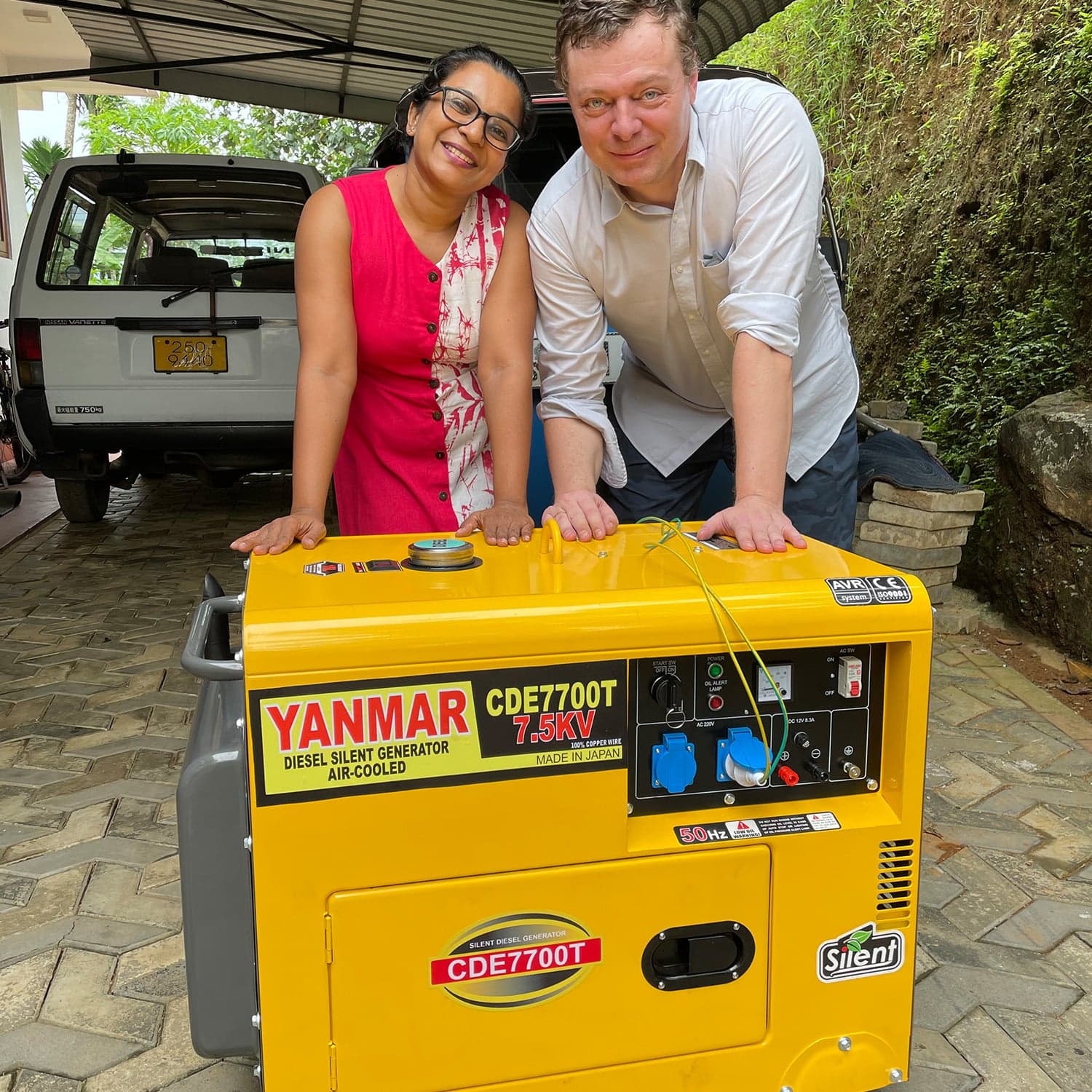 Svend and Nilanthi Thisera with stand next to a yellow Power Generator