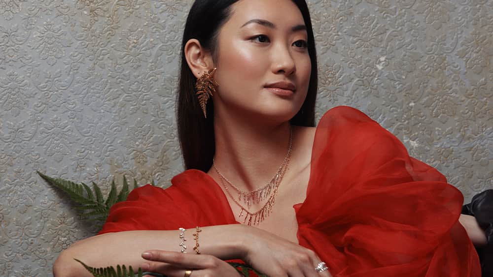 Woman wearing red dress and statement fern earrings.