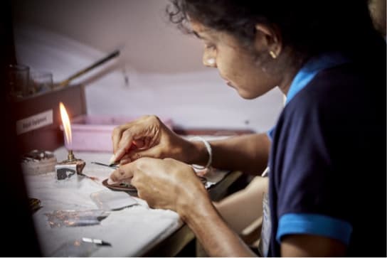 Female Lapidarist cutting facets into a rough Sri Lankan mined sapphire.