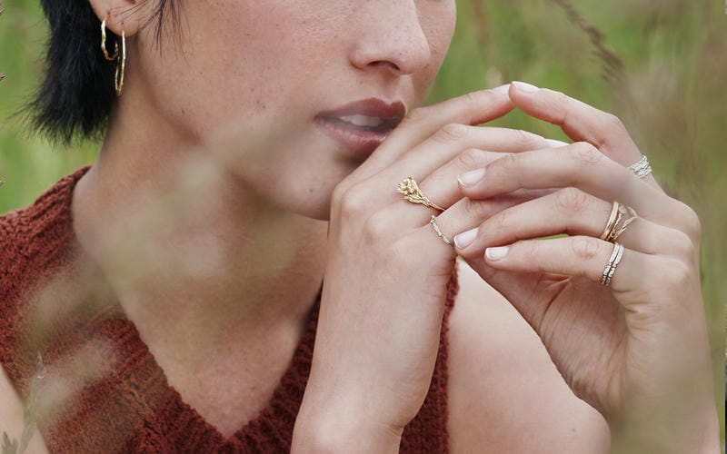 Jeweller setting diamonds and a green sapphire into a solid gold ring.