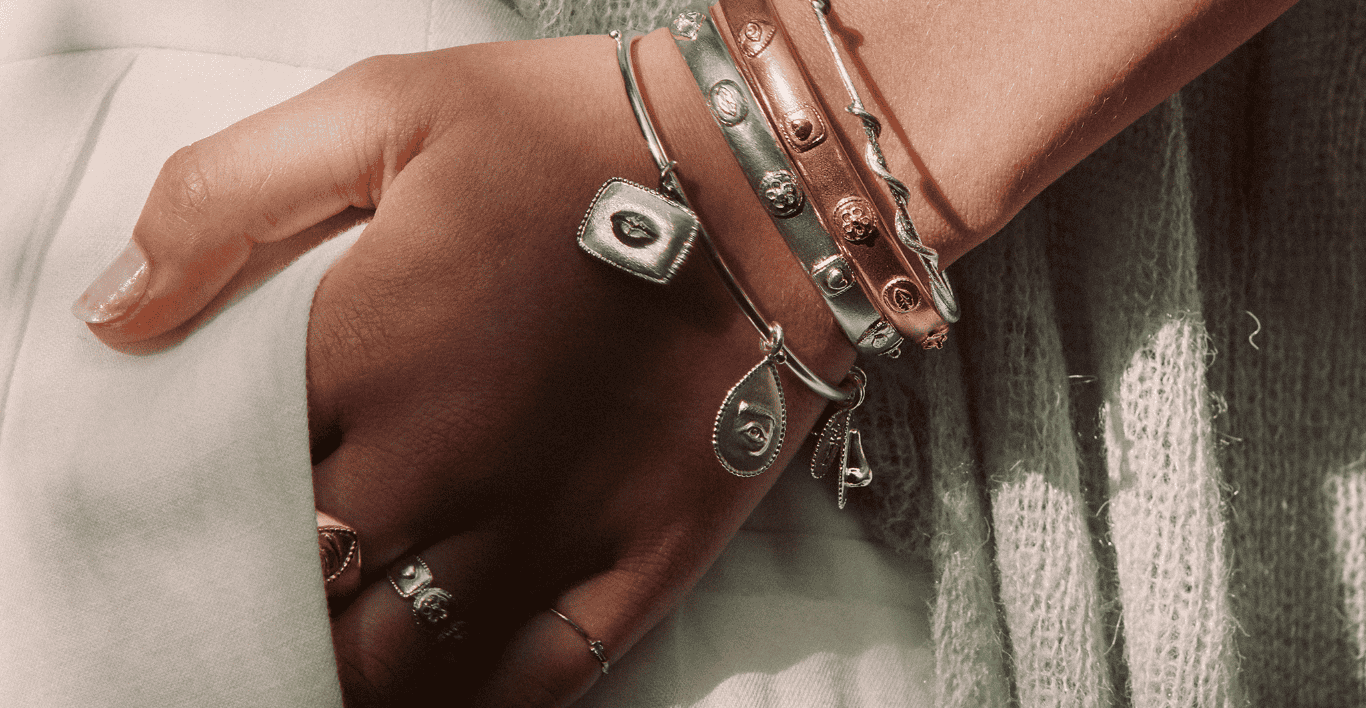 Close up of a Salt and Pepper shakers necklace held up to the camera by a woman wearing green knit top.